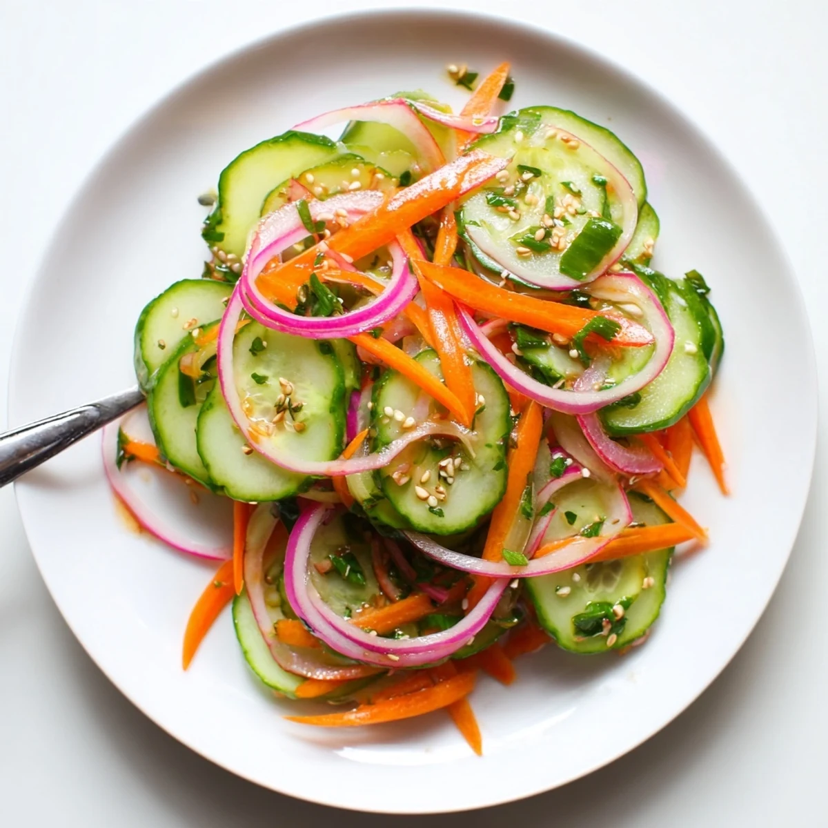 Colorful cucumber salad remix featuring carrots and scallions, garnished with sesame seeds.  