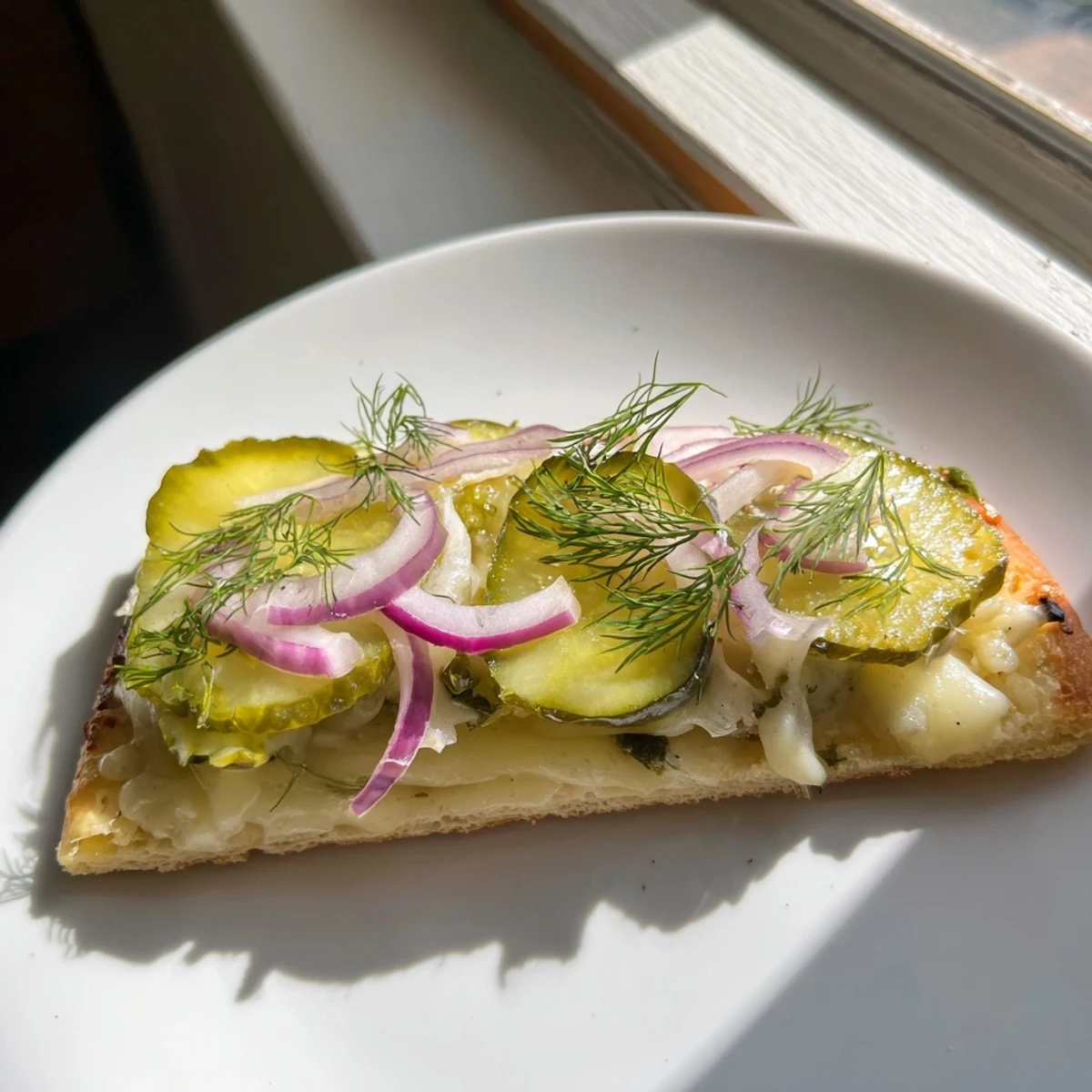 Tangy Pickle Pizza topped with creamy sauce and crispy dill for unique flavor.  