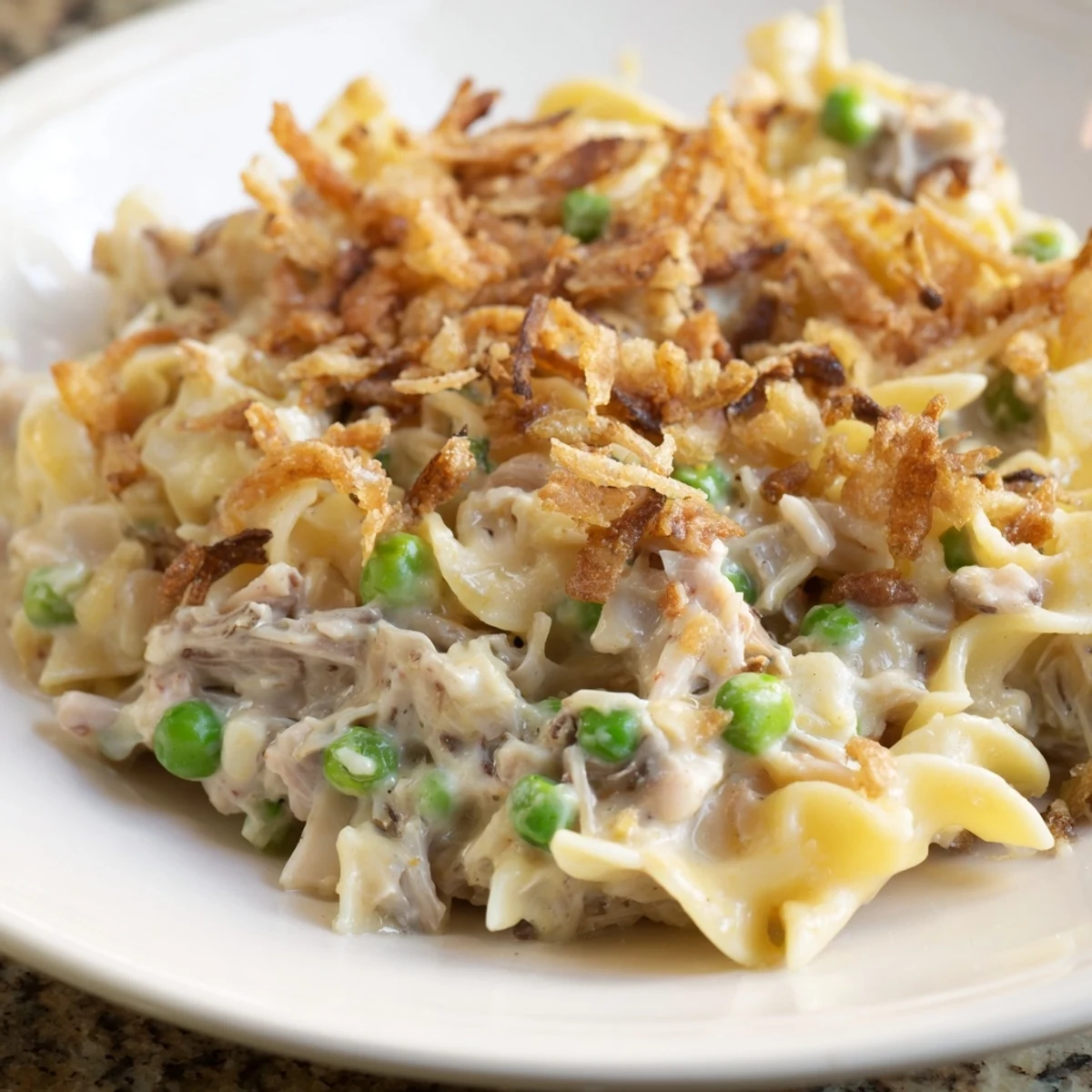 Golden-brown tuna noodle casserole boasting a crispy onion topping, perfect for sharing at dinner.