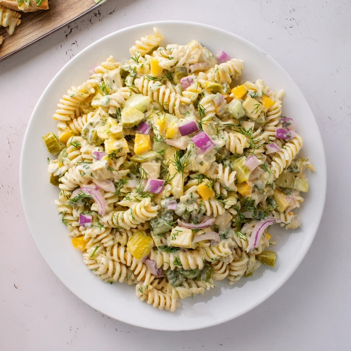 Creamy Dill Pickle Pasta Salad with cheddar, red onion, and herbs, ready to serve cold.