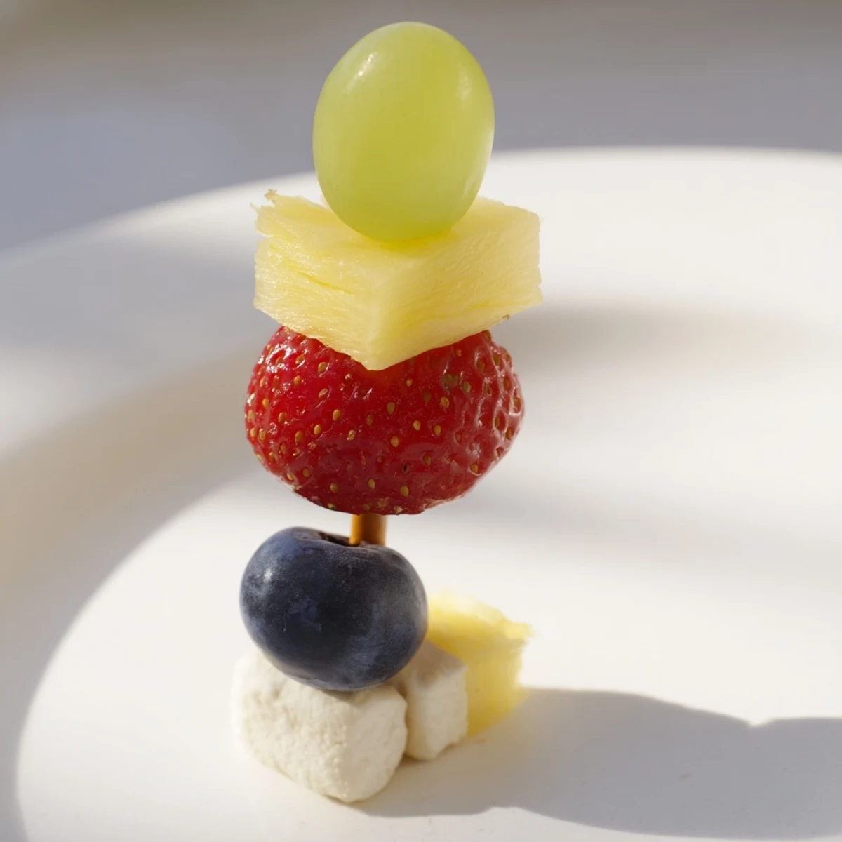 Vibrant Christmas Light Fruit Skewers feature bright red strawberries, green grapes, and sweet pineapple chunks.