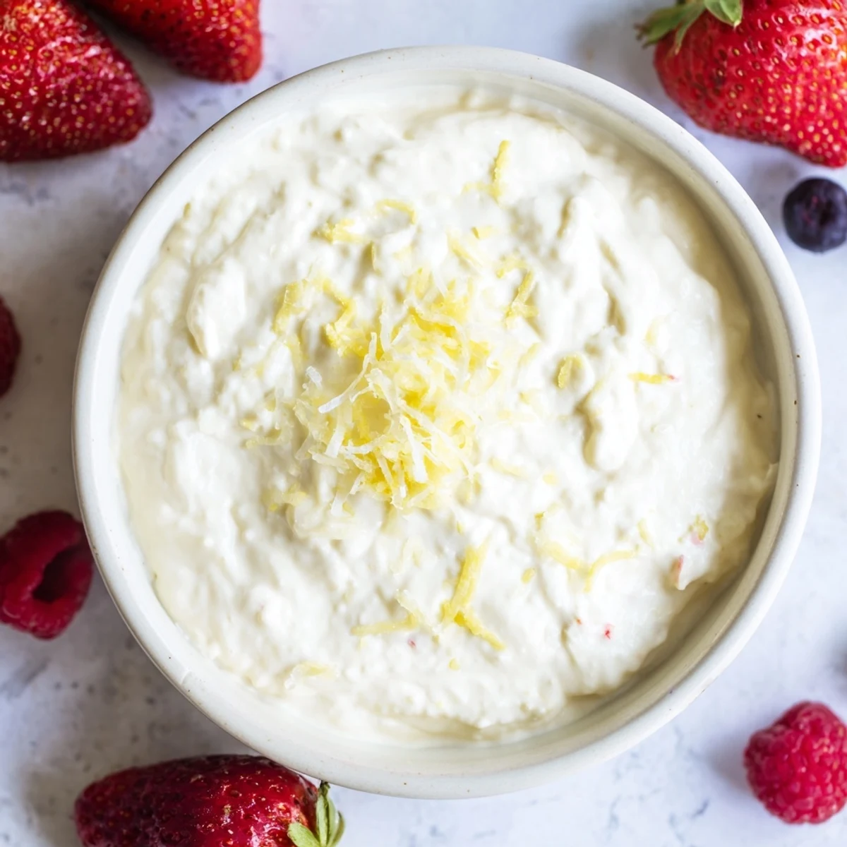 This vibrant, colorful image showcases Easy Fluffy Cream Cheese Fruit Dip served elegantly with berries and lemon zest.