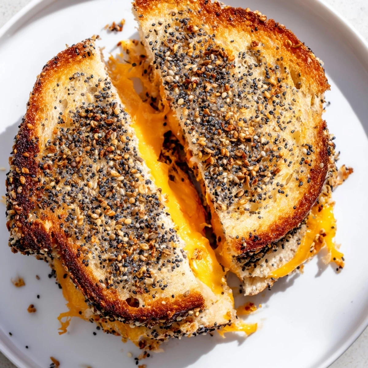 Golden, melted Everything Bagel Grilled Cheese oozing with cheddar, ready to be sliced and served.