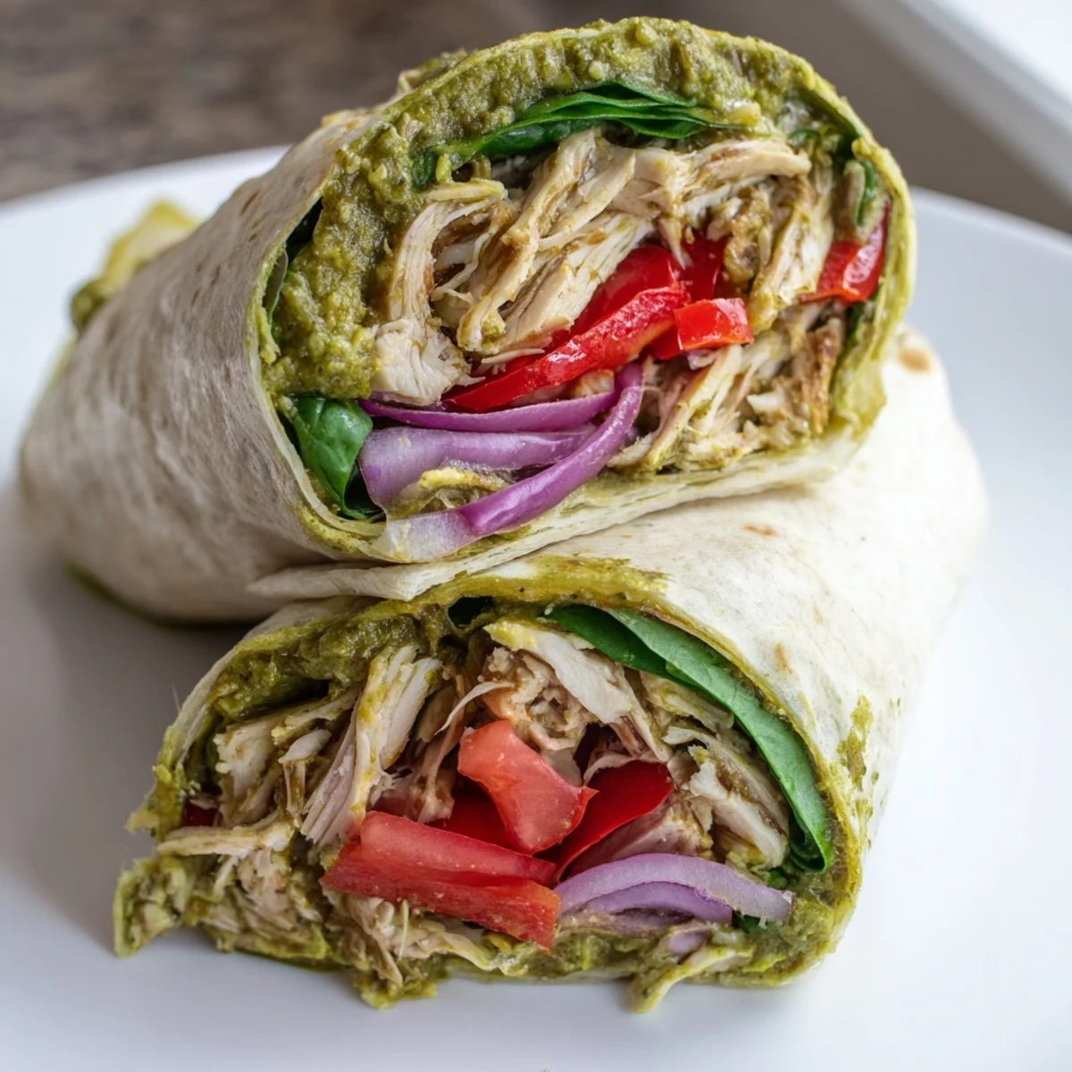 Freshly made Pesto Chicken Wrap, with visible layers of vibrant veggies and creamy mozzarella cheese.
