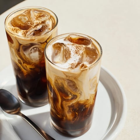 Creamy tahini iced coffee topped with plant-based milk and ice cubes.  