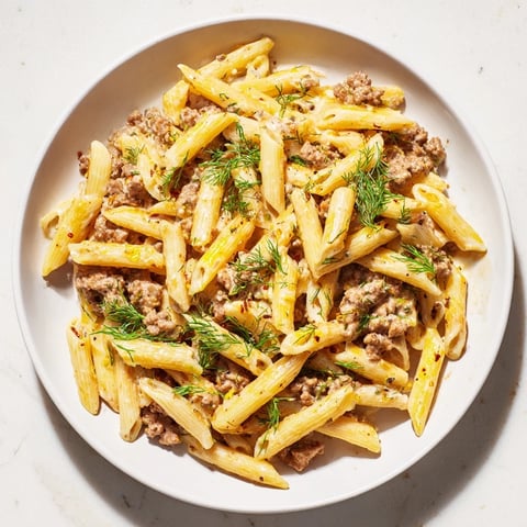 Steaming Turkish Pasta with Ground Turkey, glistening with paprika butter and fresh herbs for enjoyment.