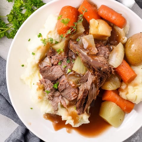 Slow Cooker Pot Roast with Mashed Potatoes served with rich gravy and vibrant vegetables.
