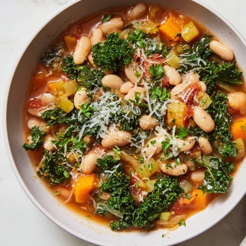 Close-up of hearty Italian Bean & Kale Stew, garnished with fresh parsley and Parmesan cheese.