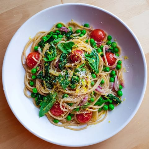 A comforting bowl of Spring Veggie One-Pot Spaghetti, garnished with fresh basil and Parmesan cheese for a vibrant dinner.  