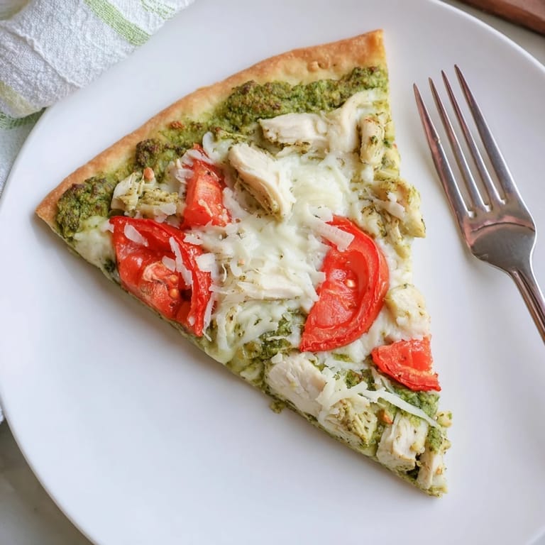 A freshly baked Chicken Pesto Pizza, featuring tender chicken, vibrant pesto, and bubbling cheese, ready to be served.