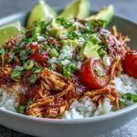 Salsa Chicken Bowls with shredded chicken, black beans, and corn, topped with fresh avocado and cilantro.  