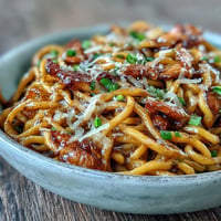 Caramelized onions top spicy French Onion Buldak Noodles with melted Gruyère.
